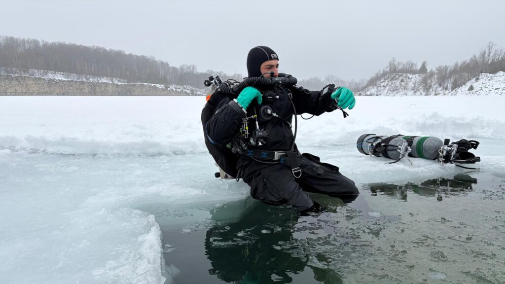 Diver in drysuit entering ice water at Guelph quarry Ontario